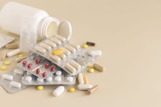 Mix of pills and capsules in a aluminum and plastic blisters with some missing pills already used on light beige close up, copy space. Preventive medicine and healthcare, dietary supplements