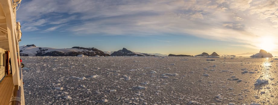 Cruise ship sails through wintry Cierva Cove - a deep inlet on the west side of the Antarctic Peninsula, ringed by Cierva Bay in San Martín Land - Antarctica, during a dramatic sunset