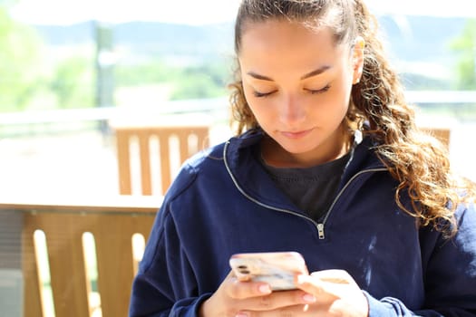 Front view portrait of a concentrated woman using smart phone in a restaurant terrace