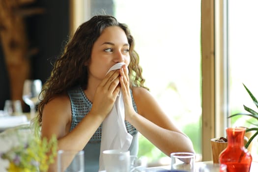 Woman cleaning mouth with a napkin sitting in a restaurant