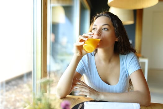 Woman drinking orange juice from glass in a restaurant or home