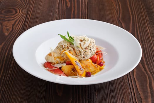 Fried turkey meat with roasted tomato and bell pepper served with parmesan, cranberry and orange balsamic sauce on dark wooden background