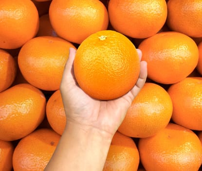 hand holding orange fruit on background orange fruit