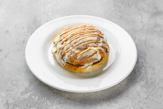 Fresh cinnamon bun with sugar icing and caramel