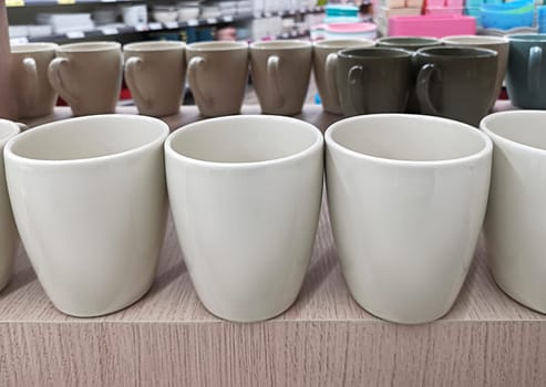 Focus on foreground of many various ceramic mugs display for sale at outdoor market