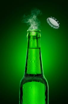 cold wet open beer bottle with smoke on green background
