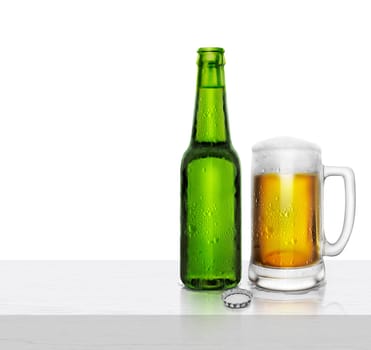 Glass and bottle of beer with water droplets on white wooden table