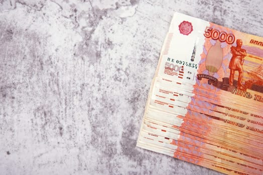 Russian cash banknotes worth five thousand rubles, the bundle lies on a gray background, there is a place for an inscription and text. Layout, mockup.
