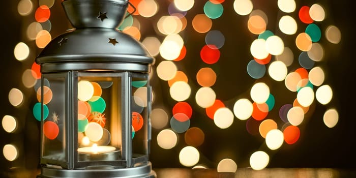 Christmas composition: a lantern with candles, and blurred bokeh lights in the background.