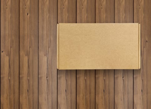 Cardboard box on wooden floor, top view. Space for text