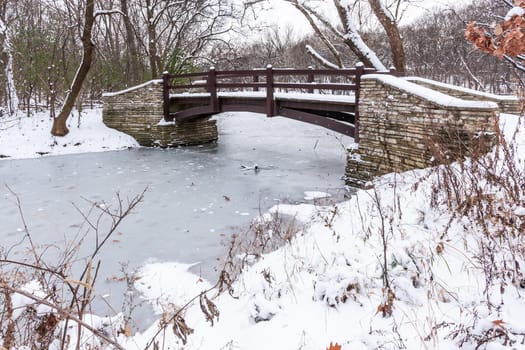 Rustic Bridge Over Frozen River In Winter.