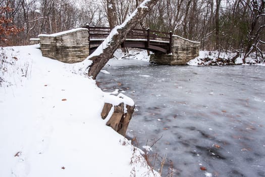 Rustic Bridge Over Frozen River In Winter.