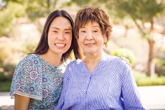 Outdoor portrait of a happy Chinese mother and daughter.