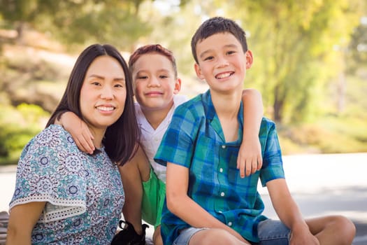 Outdoor portrait of biracial Chinese and Caucasian brothers and their mother.
