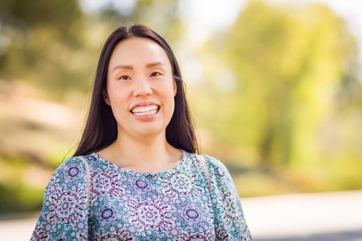 Outdoor portrait of a happy Chinese young adult woman.