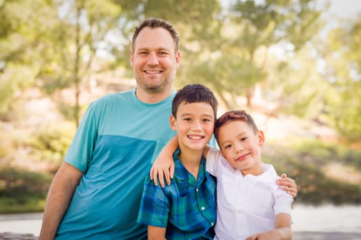 Outdoor portrait of biracial Chinese and Caucasian brothers and their father.
