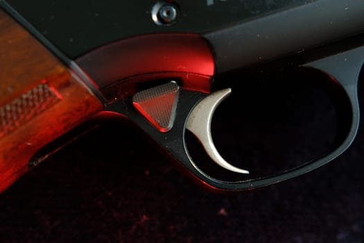 Trigger of a rifle on black background with red lightning.