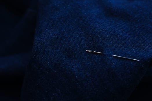 Sewing thread and needle at jeans denim background texture. Tailor handmade jeans denim concept.