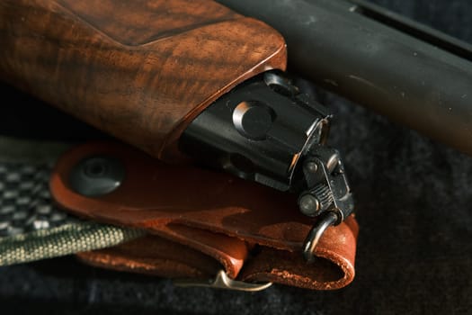 shell magazine into the barrel of a long shotgun on dark background with leather belt.