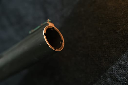 Muzzle of shotguns. Shotgun - macro shooting. Muzzle end of the barrel with green bead on the end on a black cloth background.