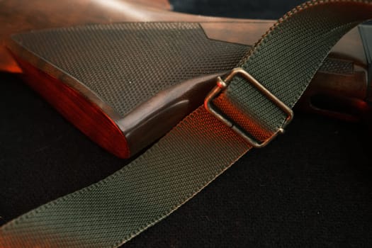 Closeup of a wooden shotgun butt. Hunting semi-automatic shotgun with a wooden button dark background with red light.