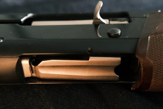 Closeup shotgun shutter. Hunting semi-automatic shotgun with wooden butt on dark background.