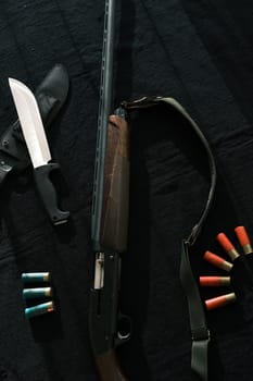 Weapon on black cloth: knife, rifle, shells,top view. Top view of knife, rifle shells