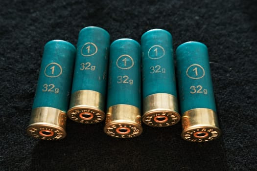 Shotgun shells on a black surface. Ammunition for 12 gauge smoothbore weapons. Hunting ammunition. Dark background
