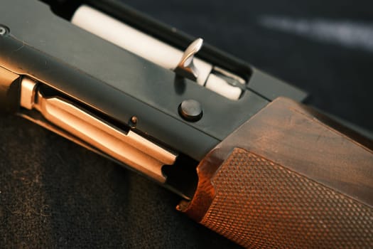 Closeup shotgun shutter. Hunting semi-automatic shotgun with wooden butt on dark background.