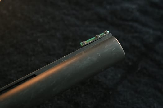 Muzzle of shotguns. Shotgun - macro shooting. Muzzle end of the barrel with green bead on the end on a black cloth background.