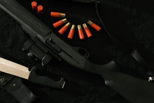 Weapon on black cloth: knife, rifle, shells,top view. Top view of knife, rifle shells