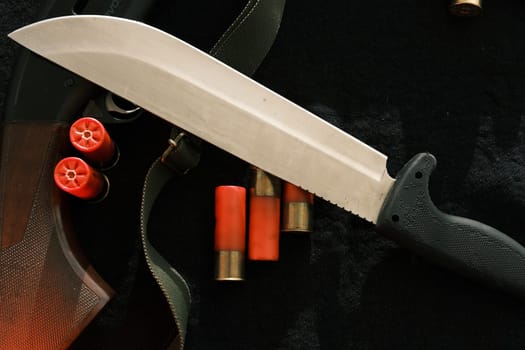Weapon on black cloth: knife, rifle, shells,top view. Top view of knife, rifle shells