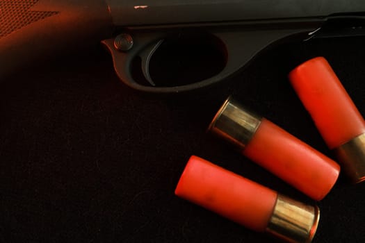 Trigger of a rifle on black background with red lightning with Shotgun shells on a black surface. Ammunition for 12 gauge smoothbore weapons. Hunting ammunition. Dark background