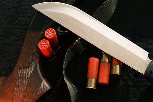 Weapon on black cloth: knife, rifle, shells,top view. Top view of knife, rifle shells