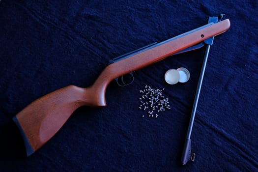 Rifle gun break in two with air pellets for hunting on cloth dark background.