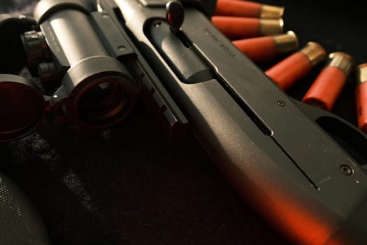 Closeup shotgun shutter. Hunting semi-automatic shotgun with wooden butt on dark background.