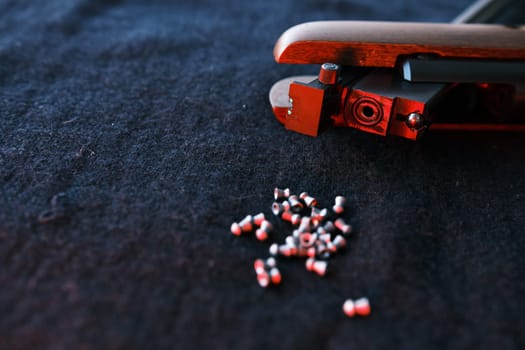 Rifle gun break in two with air pellets for hunting on cloth dark background with red light close up of rifle shutter hole.