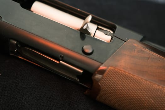 Closeup shotgun shutter. Hunting semi-automatic shotgun with wooden butt on dark background.