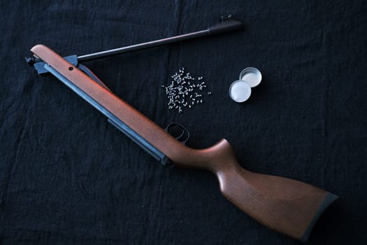 Rifle gun break in two with air pellets for hunting on cloth dark background.
