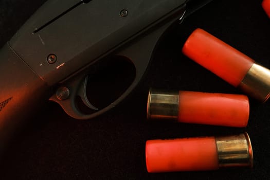 Trigger of a rifle on black background with red lightning with Shotgun shells on a black surface. Ammunition for 12 gauge smoothbore weapons. Hunting ammunition. Dark background