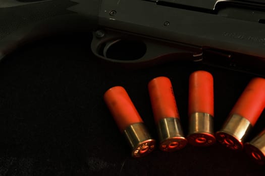 Trigger of a rifle on black background with red lightning with Shotgun shells on a black surface. Ammunition for 12 gauge smoothbore weapons. Hunting ammunition. Dark background