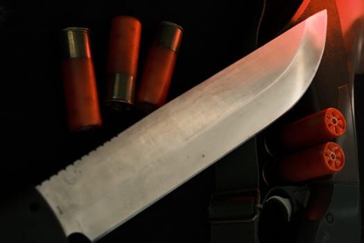 Weapon on black cloth: knife, rifle, shells,top view. Top view of knife, rifle shells