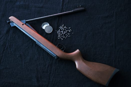 Rifle gun break in two with air pellets for hunting on cloth dark background.