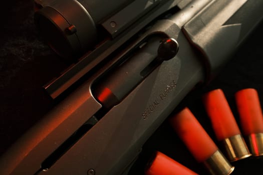 Closeup shotgun shutter. Hunting semi-automatic shotgun with wooden butt on dark background.