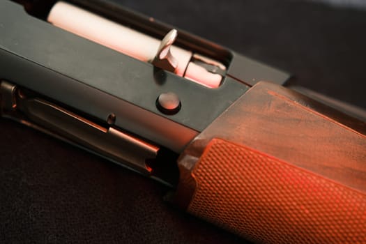 Closeup shotgun shutter. Hunting semi-automatic shotgun with wooden butt on dark background.