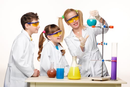 Teens and teacher of chemistry at chemistry lesson making experiments isolated on white background