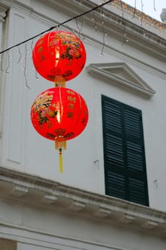 Two Chinese lanterns hanging in front of colonial house window
