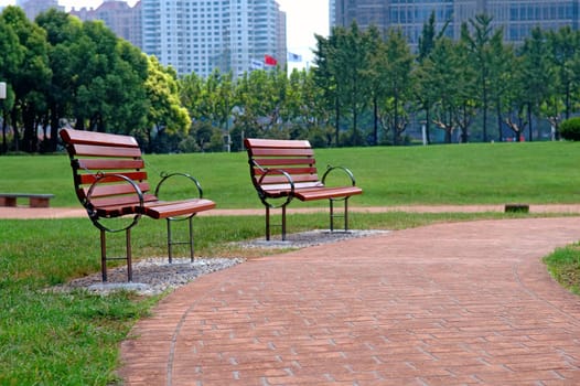 The walk way and bench of city park with building as background