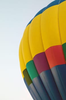 Close up of portion of rainbow colored hot air balloon against sky.