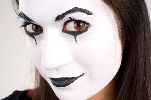 Woman made up in white face looks right into the camera
